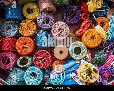 Una serie di colori in una scatola da cucire con fili di varie lunghezze e spessori. Foto Stock