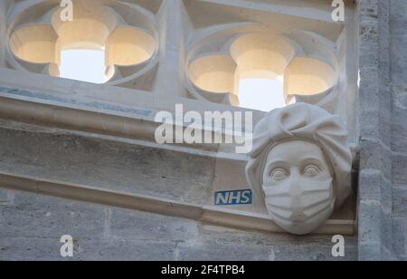 Un'incisione di un operaio NHS indossante maschera sul lato del Priorato di Christchurch in Dorset durante il terzo blocco nazionale dell'Inghilterra per frenare la diffusione del coronavirus. La scultura è un tributo permanente agli sforzi del servizio sanitario durante la pandemia ed è stata aggiunta al Priorato - la cui storia risale alla metà del 11 ° secolo - come parte di un progetto per sostituire i gargoyle danneggiati e grottesche. Data immagine: Martedì 23 marzo 2021. Foto Stock