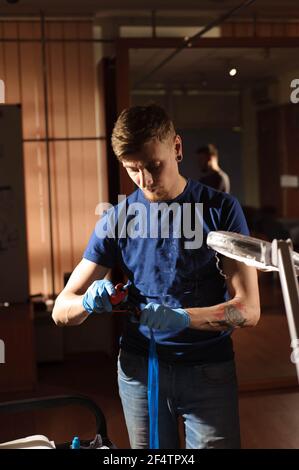 Tattoo Artist creando un tatuaggio su un uomo di braccio. Foto Stock