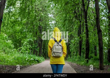 Ha girato indietro una giovane donna in un cavallino giallo della felpa nella foresta di estate. Gita in una foresta. Foto Stock