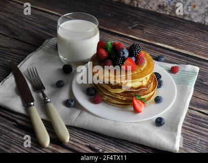 Sana colazione di frittelle con frutti di bosco, latte su un asciugamano da cucina. Foto Stock