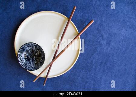 Disposizione piatta di ciotole vuote e piatti con bastoncini tabella blu Foto Stock