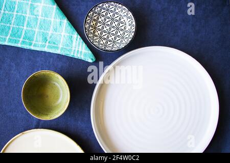 Disposizione piatta di ciotole e piatti vuoti su tavolo blu Foto Stock