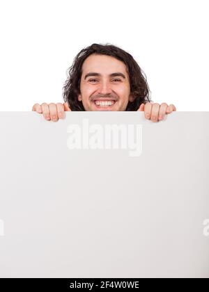 Ritratto closeup, uomo sorridente in piedi dietro un banner vuoto per la pubblicità e i messaggi, aspetto allegro alla fotocamera. Ragazzo felice che tiene una shee vuota Foto Stock