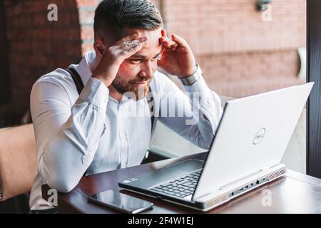 Giovane uomo d'affari che guarda lo schermo di un laptop preoccupato Foto Stock