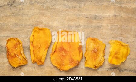 fette di frutta secca di mango contro carta testurizzata di corteccia con uno spazio per la copia Foto Stock