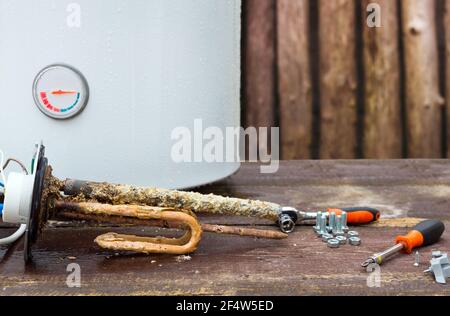 scaldabagno rotto con elementi riscaldanti, su fondo in legno. Foto Stock