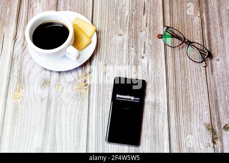 Un telefono cellulare o un telefono cellulare posato su un legno Tabella con l'app Investing.com aperta sullo schermo Foto Stock