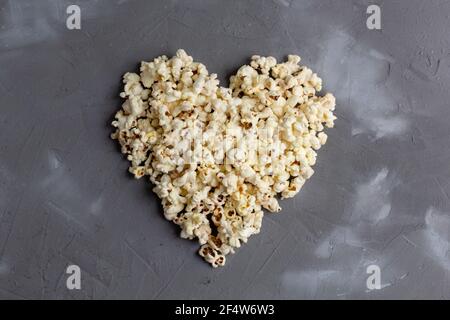 Popcorn a forma di cuore su sfondo grigio di pietra. Film d'amore. Vista dall'alto. Foto Stock