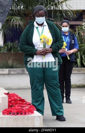 Il personale tiene i fiori da collocare ai piedi della statua dell'infermiera della Guerra di Crimea Mary Seacole durante una cerimonia per osservare un minuto di silenzio al St Thomas' Hospital, nel centro di Londra, Come parte della Giornata Nazionale di riflessione, nell'anniversario del primo blocco nazionale per prevenire la diffusione del coronavirus. Data immagine: Martedì 23 marzo 2021. Foto Stock