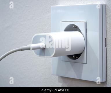 Primo piano di un caricabatteria per telefono cellulare collegato a un uscita Foto Stock