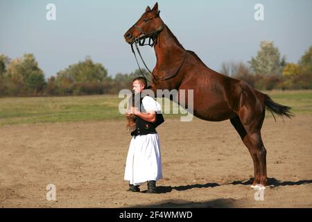 PUSZTA, UNGHERIA, SETTEMBRE 04. 2020: Pastori ungheresi come csikos in costume tradizionale folk che mostra i suoi cavalli addestrati nel puszta lowl ungherese Foto Stock