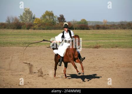 PUSZTA, UNGHERIA, SETTEMBRE 04. 2020: Pastori ungheresi come csikos in costume tradizionale folk che mostra i suoi cavalli addestrati nel puszta lowl ungherese Foto Stock