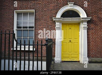 Edificio in vecchio stile georgiano con facciata di mattoni e una porta d'ingresso ad arco di giallo luminoso su Merion Square Dublin, Irlanda. Foto Stock