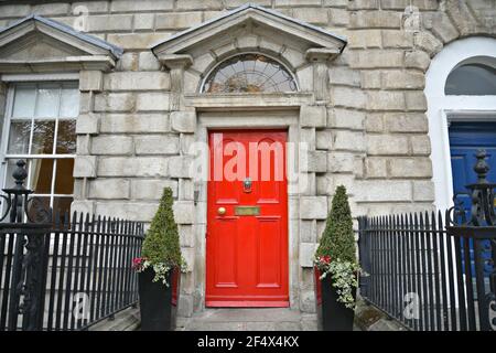 Edificio in pietra di stile Georgiano con una porta d'ingresso di colore rosso luminoso e un manico in ottone su Merion Square Dublin, Irlanda. Foto Stock