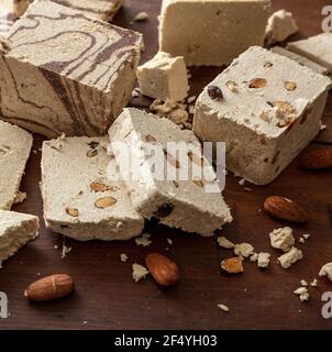 Halva varietà cacao e mandorle su sfondo tavola di legno. Halvah alla vaniglia o halwa pezzi con noci, closeup, confezione tradizionale dessert fatto wit Foto Stock