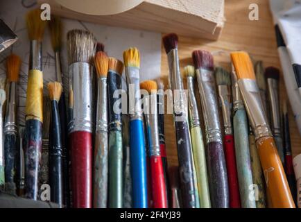 Concetto di pittura. Pittori artisti utilizzati, strumenti sporchi per disegnare su tavola di legno, sfondo sfocato. Accessori per arte creativa e disegnata a mano Foto Stock