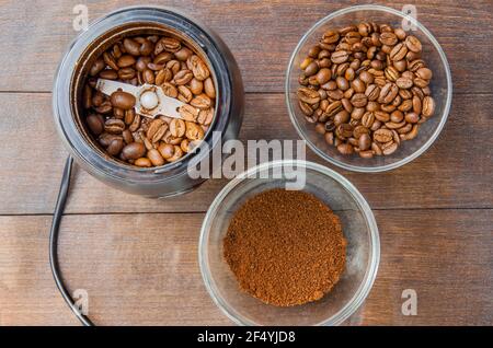 I chicchi di caffè nel mulino e il caffè messo a terra nel ciotola sullo sfondo scuro vista dall'alto Foto Stock