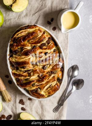 Scena pomeridiana con brioche vegane preparate al momento e budino di mele con uvetta, albicocche secche e crema pasticcera adagiata su un tavolo, pronto per essere servito. Foto Stock