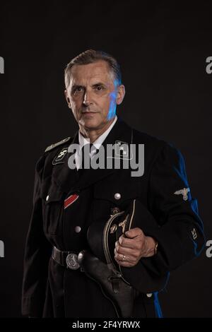 Uomo attore in divisa militare storica come ufficiale dell'esercito tedesco  durante la seconda guerra mondiale, che posa su uno sfondo nero in una luce  blu scenografica Foto stock - Alamy