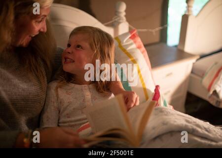 Buona madre e figlia che leggono la storia di addormentarsi a letto Foto Stock