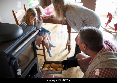 Famiglia che rimuove i biscotti caldi freschi dal forno Foto Stock