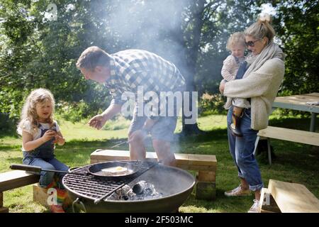 Barbecue per famiglie alla griglia in cortile soleggiato Foto Stock