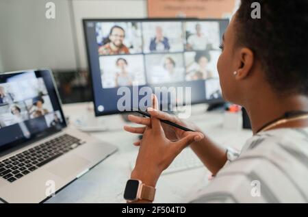 Videoconferenza di una donna d'affari su laptop e computer in ufficio Foto Stock