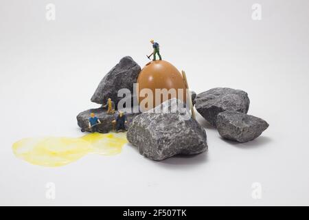 Primo piano di piccole figure di minatori che lavorano con rocce su sfondo bianco Foto Stock