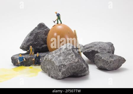 Primo piano di piccole figure di minatori che lavorano con rocce su sfondo bianco Foto Stock