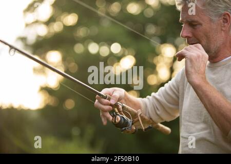 Uomo che prepara la lenza di pesca del mosca Foto Stock