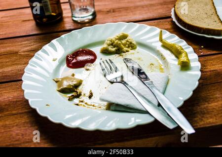 Piatto sporco dopo il pasto finito con ketchup, senape e salse di rafano intatti Foto Stock