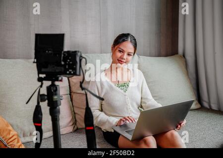 Blogger asiatico, podcaster o vlogger guardando la fotocamera e parlando di riprese video con la tecnologia. Persone influenti sui social media o produttori di contenuti Foto Stock