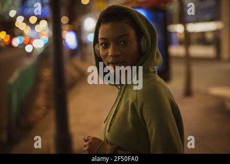 Ritratto sicuro giovane donna in felpa con cappuccio sul marciapiede della città a. notte Foto Stock