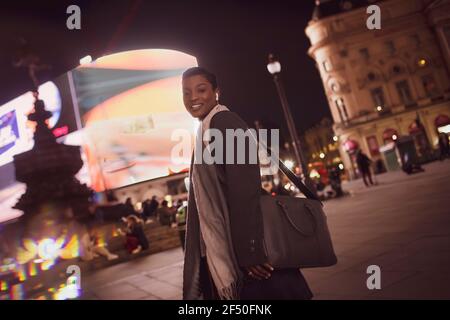 Ritratto felice giovane donna in città di notte, Londra, Regno Unito Foto Stock