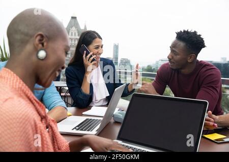 Gli uomini d'affari che parlano e lavorano con i computer portatili sul balcone Foto Stock