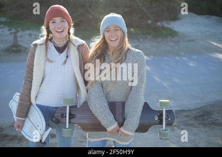 Ritratto Felice giovane donna amici in cappelli in maglia con skateboard Foto Stock