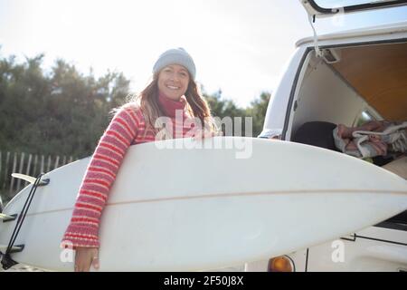 Ritratto giovane surfista carefree con tavola da surf fuori furgone Foto Stock