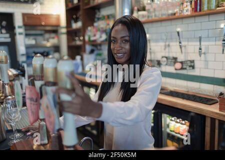 Ritratto felice giovane barista femminile dietro bar Foto Stock