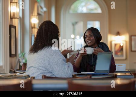 Donne d'affari che parlano e bevono caffè al computer portatile nel caffè Foto Stock