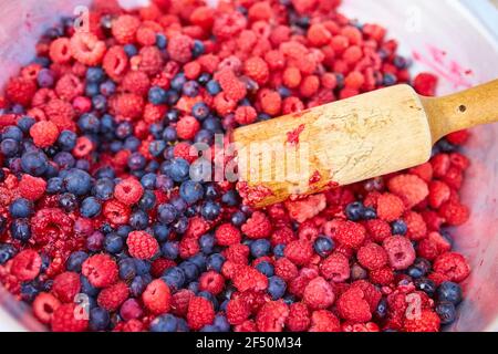 Lamponi e ribes nero in una ciotola con un pestello, facendo marmellata fatta in casa Foto Stock