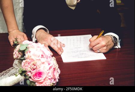 Lo sposo firma i documenti di registrazione del matrimonio Foto Stock