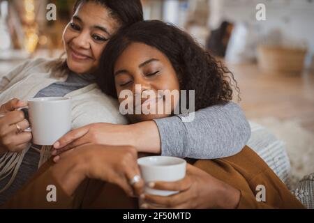 Affettuosa madre e figlia che si coccolano con il tè Foto Stock
