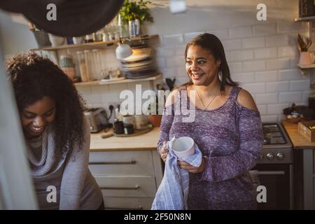 Madre e figlia che asciugano i piatti in cucina appartamento Foto Stock