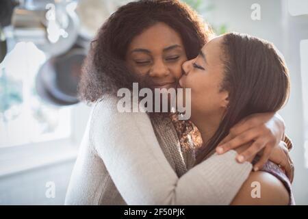Felice madre e figlia che abbracciano e baciano Foto Stock