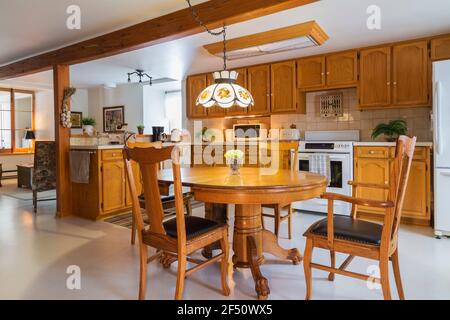 Tavolo da pranzo in legno di pino rosso artiglio con rovere rosso sedie in legno e pelle nera schienale alto in cucina con mobili in legno di quercia Foto Stock