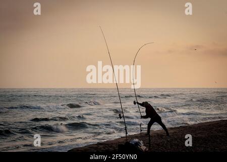 Un uomo getta la sua canna da pesca alla spiaggia di el Prat de Llobregat, Barcellona. Foto Stock