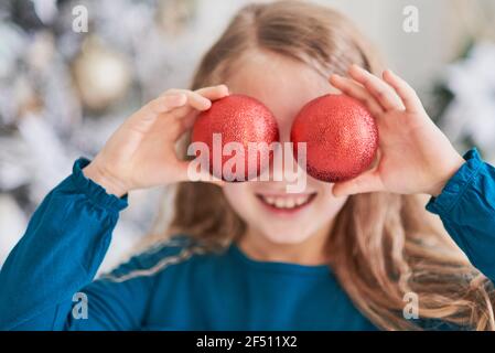 Felice ragazza eccitata bambino che tiene le palle di natale ragazza piccola felice eccitata alla vigilia di Natale. Concetto di speranza in attesa di Babbo natale. Bambino speranzoso. Nuovo Foto Stock