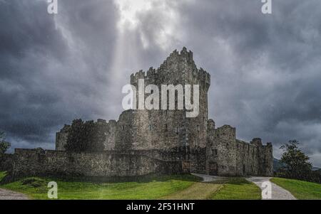 Il castello di Ross sotto la pioggia molto pesante e la tempesta di tuoni con le nuvole drammatiche, situato sulla riva di Lough Leane, Ring of Kerry, Killarney, Irlanda Foto Stock