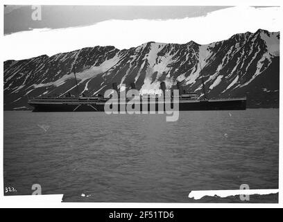 Spitzbergen, Norvegia. Il piroscafo passeggeri Hochsee "Viktoria Luise" di fronte alle montagne innevate in una baia Foto Stock